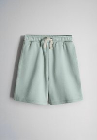 Pantalones cortos casuales de color verde claro con cintura elástica y cordón beige, mostrados sobre un fondo liso gris claro.
