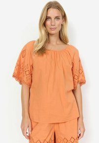 Top arancione a maniche corte con scollo rotondo, caratterizzato da dettagli in pizzo ricamato sulle maniche e sull'orlo, realizzato in tessuto leggero.
