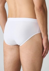 Slip di cotone bianco con una superficie liscia e senza motivi visibili, caratterizzati da una vita solida e un design aderente.