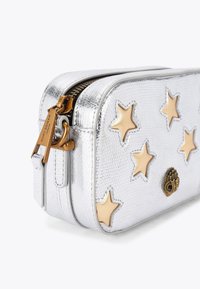 Zilveren faux leren tas met gouden sterrenapplicaties, textuur oppervlak, dubbele ritssluiting en gouden hardware details.