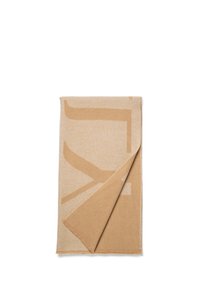 Beige deken met een groot abstract ontwerp in donkerder beige, gemaakt van zachte stof, met een omgevouwen hoek die een gladde textuur toont.
