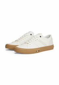 Zapatillas blancas de cuero sintético con textura suave, con puntera redondeada, suela de goma beige y un discreto detalle de logo.