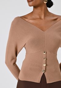 Brauner ribbenstrick Pullover mit tiefem V-Ausschnitt, tailliertem Schnitt und goldenen Knopfakzenten an der Vorderseite. Glatte Textur und dehnbarem Material.