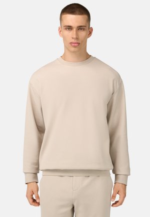 Beige sweatshirt met een ronde hals, lange mouwen en ribbelmanchetten, gemaakt van zachte stof. Eenvoudig ontwerp zonder patronen of accenten.