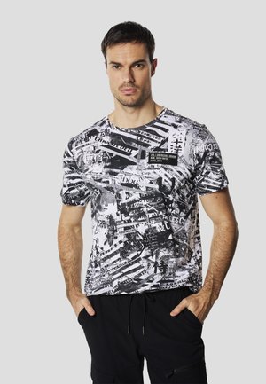 Camiseta de manga corta en blanco y negro con un estampado gráfico que incluye varios textos y patrones. Confeccionada con tela ligera y transpirable.