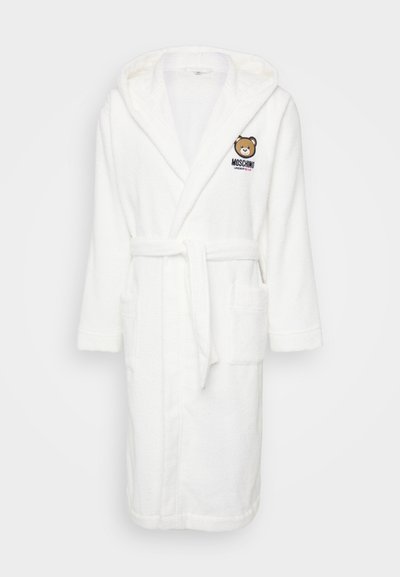 Roupa de banho de toalha branca com capuz, apresentando um logótipo de urso e o texto "MOSCHINO". Inclui um cinto para amarrar e dois bolsos frontais. Textura suave.