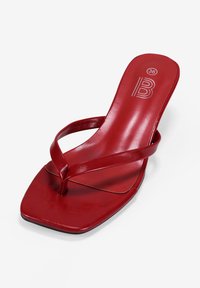 Sandalía de charol rojo, tipo flip-flop, con punta cuadrada, que presenta tiras delgadas y un pequeño tacón, marcada con la talla "36" y una "B" estilizada.