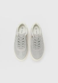 Pair of light gray suede sneakers with matching laces, white rubber soles, and "Tommy Hilfiger" branding visible inside and on tongues.