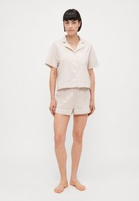 Lichtbeige pyjamapakket met korte mouwen, bestaande uit een overhemd met kraag en knopen en bijpassende shorts met een comfortabele elastische tailleband.