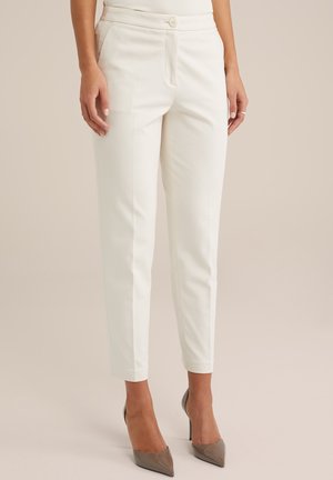 Hvide, skræddersyede, slim-fit ankellange bukser båret med beige højhælede sko, vist fra talje til fødder mod en neutral baggrund.