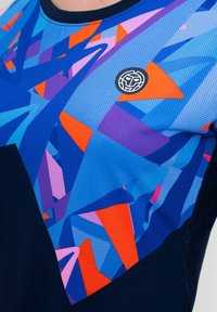 Camiseta atlética de manga corta en azul, con un patrón geométrico abstracto en naranja, rosa y morado. Tejido texturizado con cuello redondo.