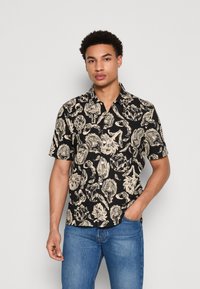 Schwarz kurzärmliges Hemd mit einem beigen Blumenmuster, klassischem Kragen und Knöpfen, kombiniert mit blauen Jeans.