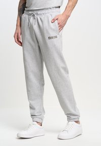 Lichtgrijze joggingbroek met een elastische tailleband, trekkoord, zijzakken en een klein "BIG STAR" logo in een donkerdere tint erop gedrukt.