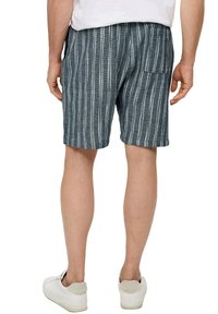 Dunkelblaue gestreifte Herren-Shorts aus Textilmaterial, mit einer Gesäßtasche und einem elastischen Bund. Getragen mit weißen Sneakers.