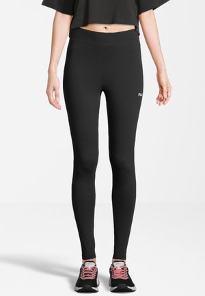 Leggings neri realizzati in materiale elasticizzato, con vita alta e un piccolo logo sul lato sinistro, abbinati a scarpe da ginnastica nere e rosa.