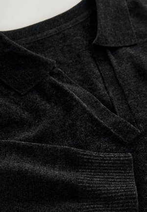 Schwarzes Poloshirt mit Kragen aus strukturiertem Stoff, ausgestattet mit einer Knopfleiste und einem gerippten Saum. Weiche Optik mit subtilen Farbvariationen.