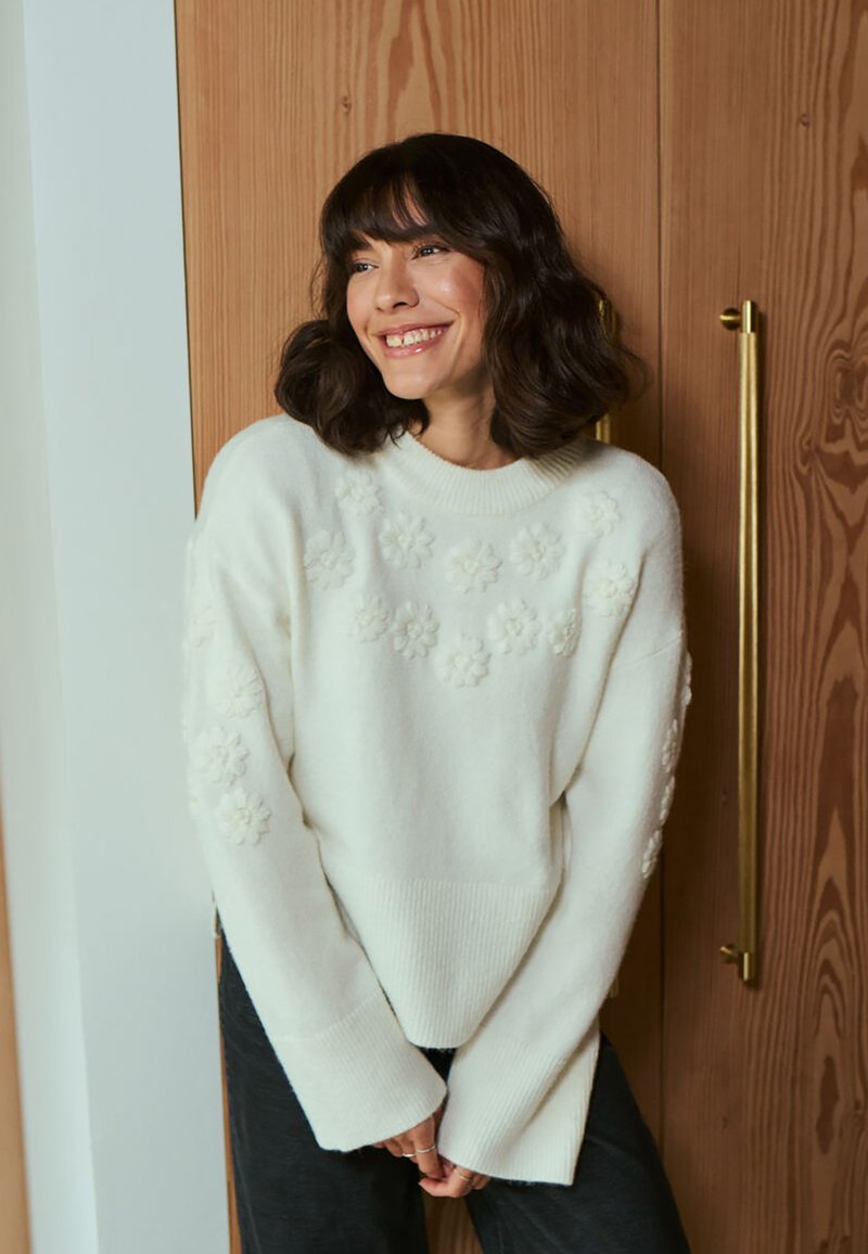 Maglione lavorato a maglia color crema con motivi floreali testurizzati, polsini e orlo a coste, vestibilità ampia e scollatura a barca.