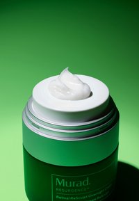 Crème de nuit Murad Resurgence Retinal ReSculpt dans un contenant cylindrique vert avec des accents argentés, surmontée d'une texture crémeuse et blanche.