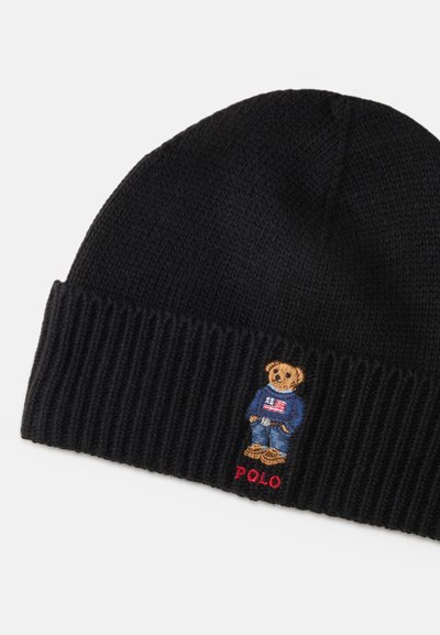 Μαύρο πλεκτό σκουφί με ριγέ μανσέτα, που διαθέτει μια κεντημένη αρκούδα που φοράει μπλε πουλόβερ, μπλε τζιν και καφέ παπούτσια, με την ένδειξη "POLO."