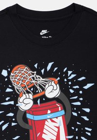 Čierne bavlnené tričko s grafickým motívom rúk, ktoré držia basketbalový kôš na roztrhnutom pozadí. Logo je výrazne zobrazené.