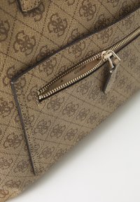 Beige structured handbag featuring a brown logo pattern, gold hardware, and a zippered pocket on the front for secure storage.