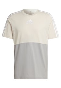T-shirt Adidas beige et gris avec un design à trois bandes blanches sur les manches et le logo Adidas centré sur la poitrine.