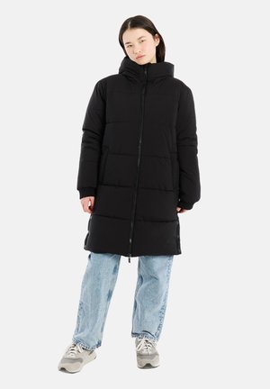 Schwarze Steppjacke mit einem durchgehenden Reißverschluss, Kapuze und strukturiertem Steppdesign. Kombiniert mit hellblauen Jeans und grauen Sneakers.