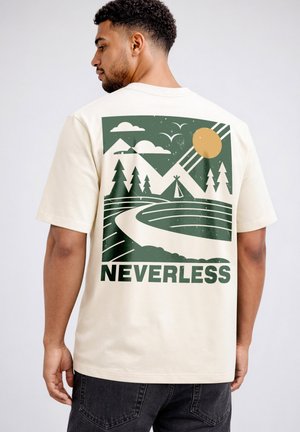 Man wearing a cream t-shirt with a green and orange graphic of mountains, trees, sun, and a winding path with the word "NEVERLESS" below.