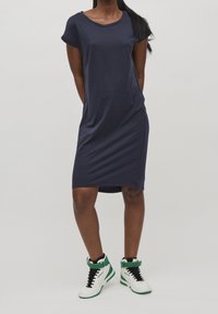 Robe bleu marine à coupe décontractée, à manches courtes et à col rond, associée à des baskets montantes blanches et vertes.