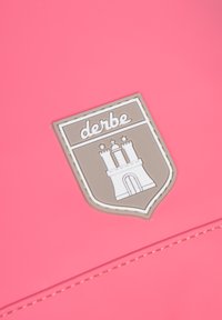 Materiale impermeabile rosa con un logo a forma di scudo raffigurante un castello. Il logo è marrone chiaro con dettagli bianchi e testo "derbe".