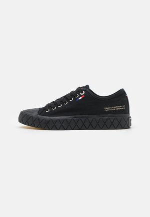 Sneaker en toile noire avec embout en caoutchouc et semelle à motif diamants. Dispose de lacets plats et d'un petit accent drapeau français sur le dessus.
