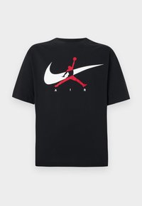 Μαύρο βαμβακερό μπλουζάκι με στρογγυλή λαιμόκοψη, με μεγάλο λευκό λογότυπο Nike swoosh και κόκκινο λογότυπο Jumpman μαζί με το κείμενο "AIR" σε λευκό χρώμα.