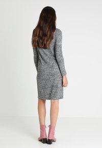 Robe longue gris à manches longues en tissu tricoté texturé, coupée au genou, associée à des bottines roses à talon bloc.