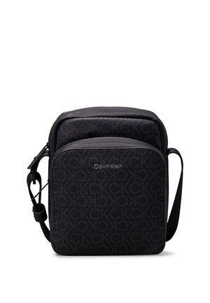 Borsa nera Calvin Klein con superficie testurizzata, motivo a logo CK in rilievo, forma rettangolare e tracolla regolabile.