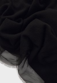 Sciarpa nera con una texture a maglia e un bordo nero liscio e trasparente. I lati presentano un delicato dettaglio a frange.