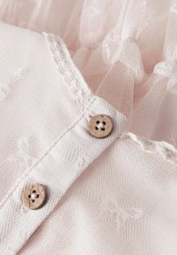 Svijetloružičasta mrežasta tkanina s teksturiranim završetkom, s čipkastim rubom i dva drvena gumba s dekorativnim rupicama.