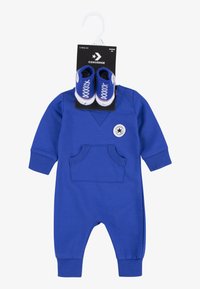 Macacão de algodão azul com mangas longas, decote em V, bolso frontal e um patch do logo da Converse; inclui sapatos de bebé azuis combinando com atacadores brancos.