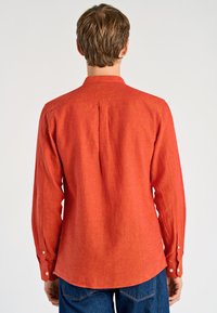 Camicia rossa a maniche lunghe in tessuto strutturato, con colletto con bottoni, piega posteriore e bottoni sui polsini.