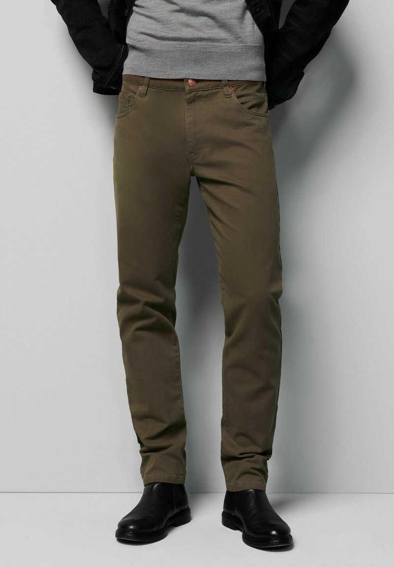 Oliwkowe bawełniane chinosy o dopasowanym kroju. Posiadają pięć kieszeni, zapięcie na guzik oraz kontrastowe stębnowanie. Stylizowane z czarnymi botkami za kostkę.