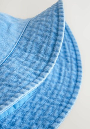 Helles blaues Bucket-Hut aus Denim, mit breiter Krempe, sichtbaren Nähten und einer strukturierten Stoffoberfläche.