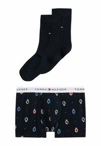 Pakke med sorte sokker og Tommy Hilfiger boxershorts, der har et mønster med farvede logoer, hvid talje og blød stoftekstur.