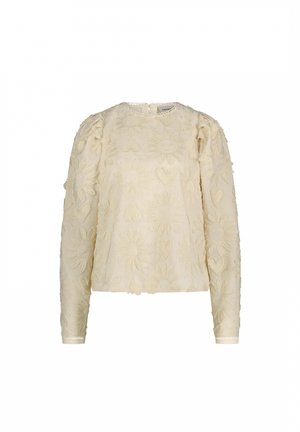 Crème blouse met intrikate bloem- en hartborduursels met zonmotieven. Rond decolleté, lange mouwen en een textuurstof.