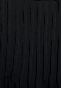 Tessuto nero a pieghe con linee verticali, caratterizzato da una superficie texturizzata e una lucentezza sottile. Il tessuto è morbido, con arricciature ben distanziate.