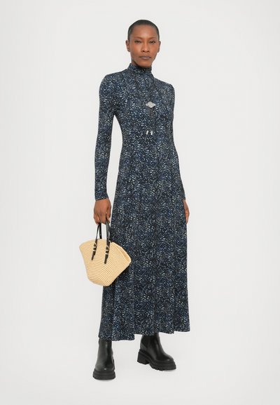 Long-sleeve navy floral dress with a high collar, textured fabric, and fitted bodice. Paired with a woven tan handbag and black ankle boots.