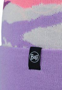 Purple knit beanie featuring a cream and pink abstract pattern. A black fabric tag with a white circular logo is attached to the bottom.