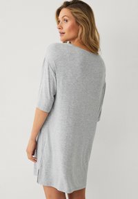 Lichtgrijze, losse jurk met korte mouwen, ronde halslijn, zijsplitten en een zachte textuur. Casual ontwerp, geschikt als loungewear.
