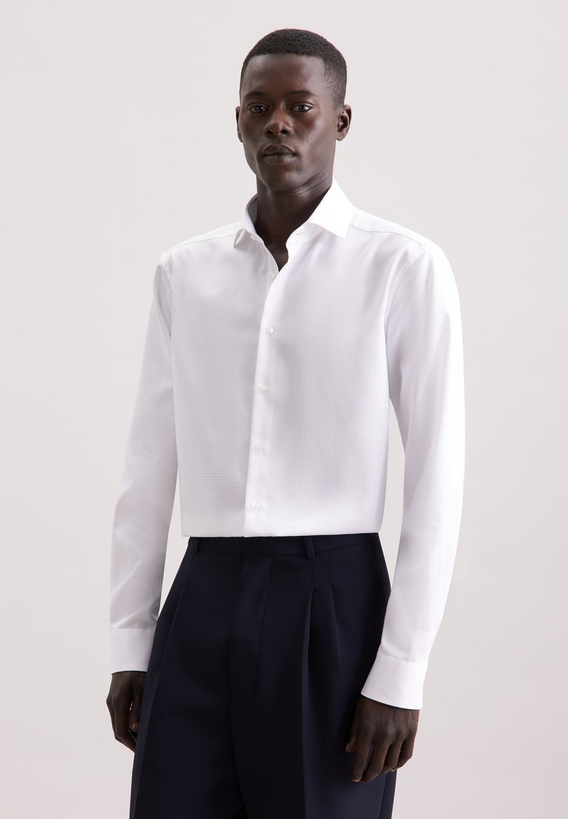 Witte overhemd met lange mouwen en een subtiele textuur, met een button-down kraag en manchetten. Gekozen in combinatie met marineblauwe broek, wat een formele stijl accentueert.
