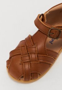 Brune lær sandaler med vævet design, justerbar rem med spænde og en glat tekstur. Rund tå og blød indersåle.