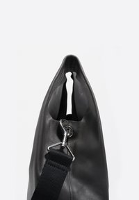 Czarna skórzana torba o unikalnym wydłużonym kształcie, wyposażona w srebrny metalowy klips i teksturowany pasek. Gładki, minimalistyczny design z otwartą górą.