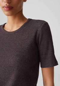 Dark brown ribbed t-shirt with short sleeves and a round neck. Fabric texture is soft and stretchy, featuring a subtle pattern.